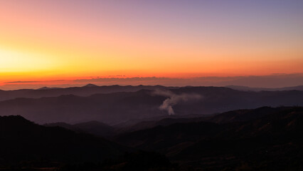 Obraz premium Majestic Sunset Gradient Sky Over Silhouetted Mountain Ranges With Fog And Smoke