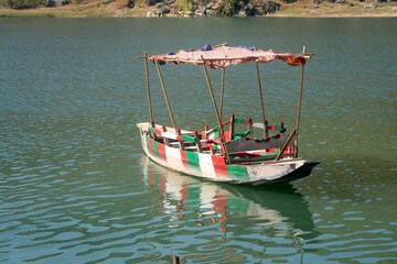 Fototapeta premium A small boat with a red, green, and white canopy floating on a serene lake