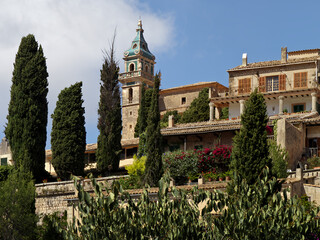 Scenic view of the Charterhouse of Valldemossa with its iconic blue-tiled bell tower under a blue sky in Mallorca, Spain