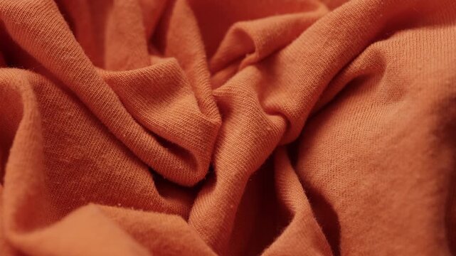 A worn orange cotton fabric with visible pilling on the textured surface. Close up.