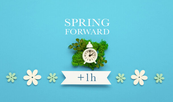 Daylight saving Time, Spring forward, Summer back concept. White Alarm Clock and Spring Daisy Flowers on Blue Background