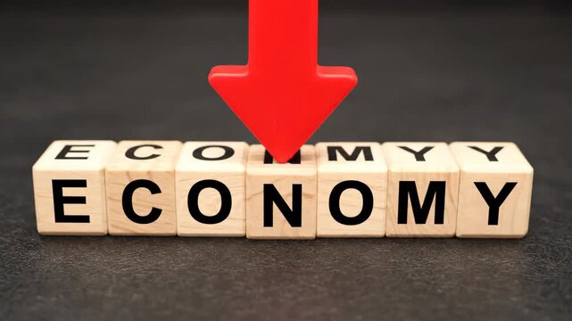 Economic crisis concept with a red arrow pointing down on wooden blocks spelling economy. Financial recession and market downturn metaphor for business and global problems