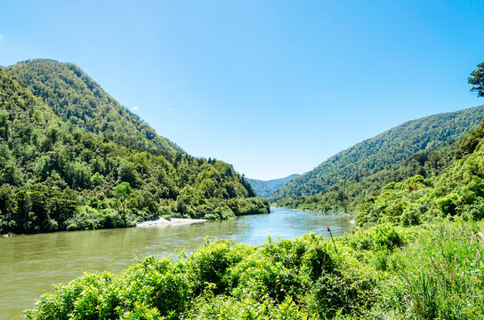 Buller Gorge in New Zealand, characterized by lush green hills and mountains on either side of a river.