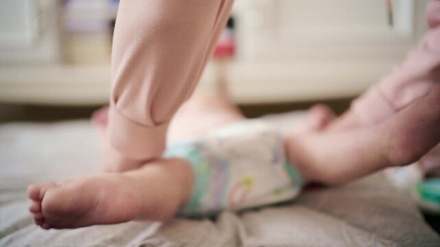 Close up of a mother gently changing a baby's diaper on a bed