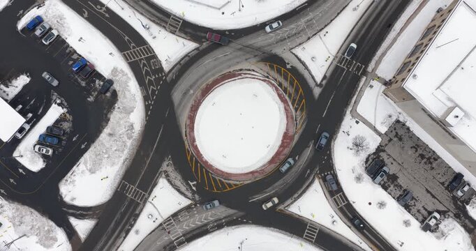 Aerial video of a urban roundabout, road, in winter with snow on the ground.