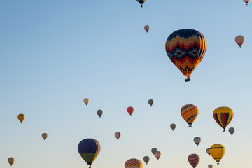 Obraz premium Colorful Hot Air Balloons Flying in Blue Sky. Hot Air Balloon Tour Under Clear Blue Sky. Adventure Travel with Hot Air Balloons. Tourism Concept – Hot Air Balloons in Open Sky.