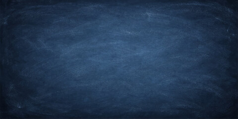 A blank vintage blue chalkboard featuring a dark grunge texture and rough weathered surface on a dirty old wall backdrop © ITS OK