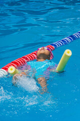 Latina girl practicing swimming with floats in an outdoor pool