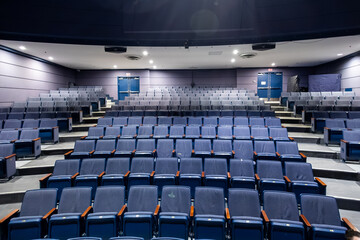 Naklejka premium Wide angle view of empty auditorium with rows of blue theater seats in modern cinema or conference hall. Indoor event venue with stage perspective and no people.
