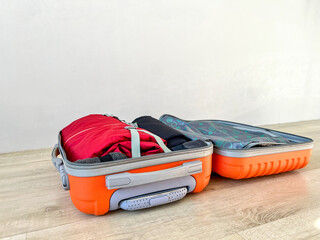 Orange suitcase open on floor packing for travel