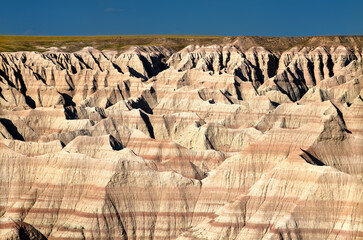 Big Badlands Overlook in Badlands National Park, South Dakota. Scenic landscape features vast eroded layered rock formations of the Badlands Wall under a blue sky