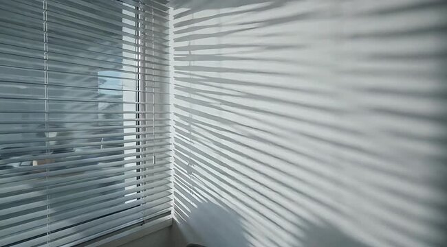 Sunlight and shadow patterns cast by blinds on a wall, creating an abstract geometric design