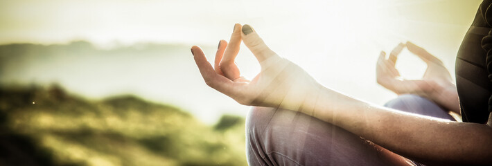 woman doing yoga in beautiful nature background at sunset or sunrise, focus on hand - mindfulness and mental health and hygiene background