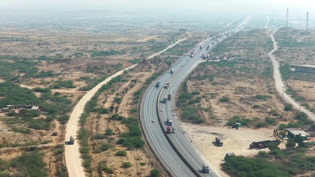 aerial drone footage of a Highway stretching through arid landscape with moving vehicles during daytime in Sindh province, Pakistan High quality drone 4k footage