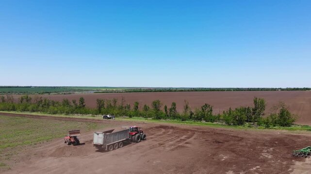 Farm tractor loading organic fertilizer into spreader trailer on field. Concept of soil health, sustainable agriculture and nutrient management.