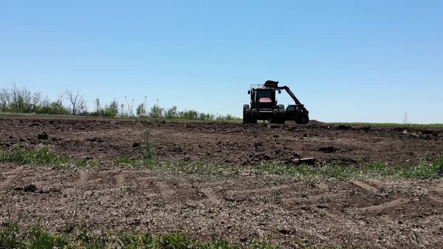 Farm tractor loading organic fertilizer into spreader trailer on field. Concept of soil health, sustainable agriculture and nutrient management.