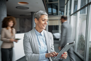 Businesswoman using digital tablet smiling at modern office