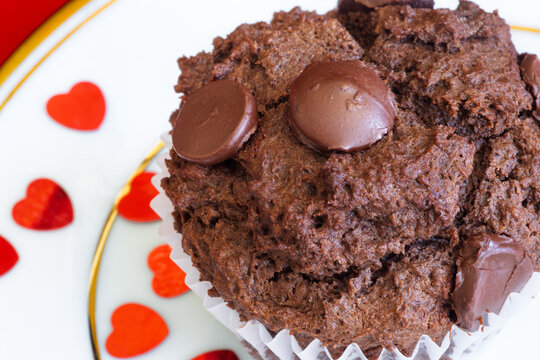 A decadent chocolate cupcake with chocolate chips set in a valentine's day backdrop.