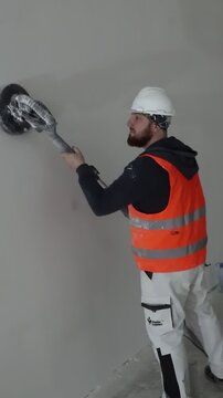 Full body slow motion shot of a construction worker sandblasting a wall, wearing complete protective gear while carefully leveling and cleaning the surface outdoors.
