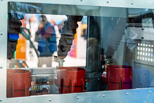 Close-up of a mechanical device, possibly lab equipment or industrial machinery Transparent front panel reveals cylindrical metallic components with red heat sinks Ambient lighting within No text