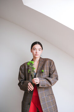 Fashionable model poses with green plant in oversized coat 