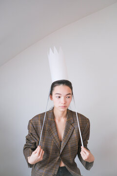 Young person wearing a paper crown in a stylish outfit at home 