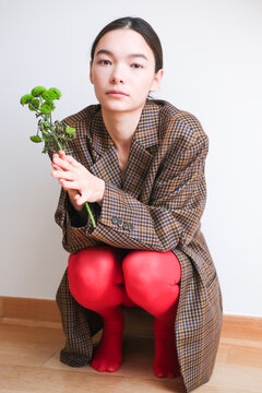 Fashionable individual poses indoors with flowers in vibrant red tight