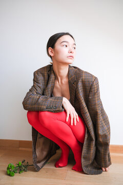 Stylish model poses in oversized brown blazer and red tights 