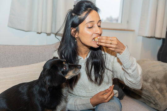 Woman Eating Pastry While Sitting With Dog