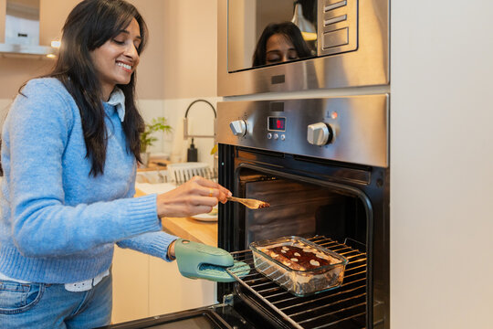 Woman Baking Brownies In Modern Kitchen Oven