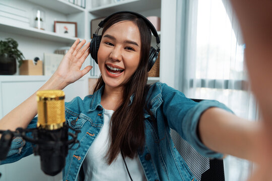 Host channel young beautiful Asian girl making selfie with smartphone wearing headphones at modern studio home office concept of behind the scene broadcaster live streaming on social media. Stratagem.