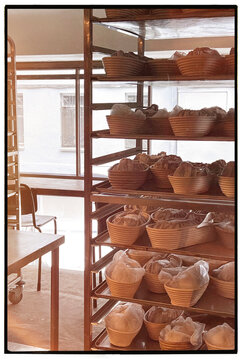 Bread preparation. Rows of baskets with dough on shelves of a bakery.