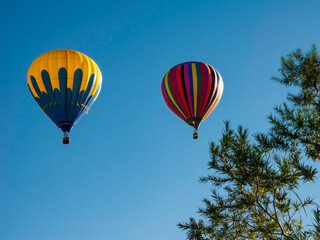 Obraz premium Two hot air balloons fly high at Albuquerque Balloon Fest in New Mexico under a clear blue sky