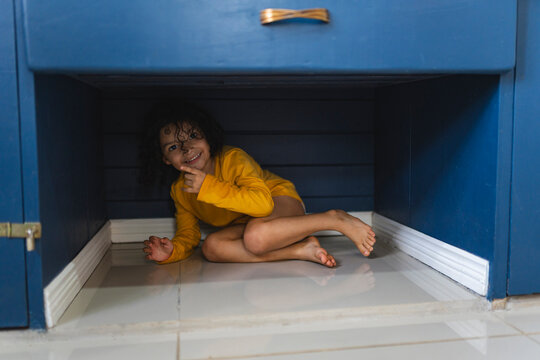 Little girl hiding under a closet