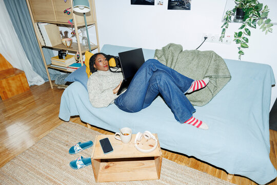 Woman at home chilling on couch using laptop.. Direct flash