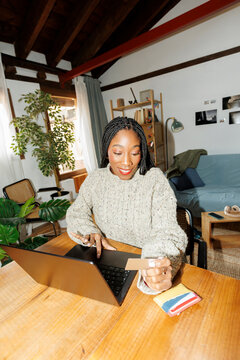 Smiling Woman shopping online using credit card