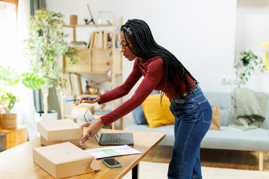Woman entrepreneur organizing packages to deliver from home office
