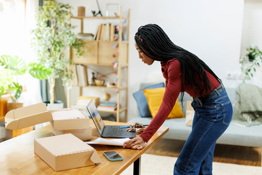 Woman entrepreneur organizing packages to deliver from home office