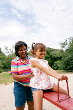 Grandmother playing with her granddaughter on the seesaw