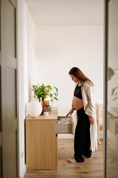 Pregnant Woman Sorting Baby Items in Cozy Nursery