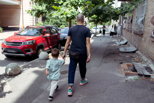 father and little son are walking down the street