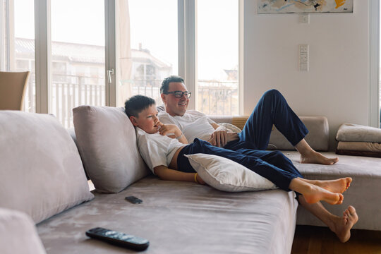 Father and son relaxing on the couch watching TV