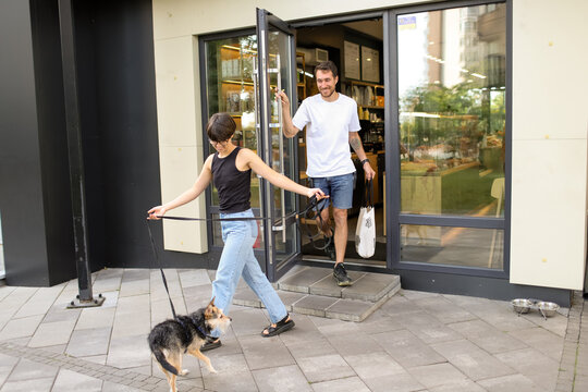 a young couple with a dog leave the cafe