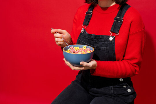 Woman Eating Colorful Cereal in a Blue Bowl with Red Background

