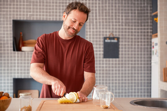 Happy man cutting lemon in the kitchen