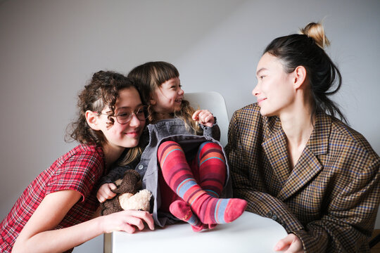 Three smiling family members sharing a joyful moment in a cozy indoor 
