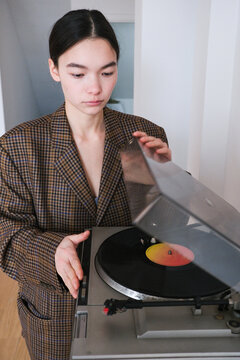 Young woman carefully places vinyl record on turntable 