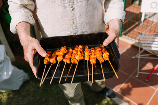 Senior man holding chicken skewers