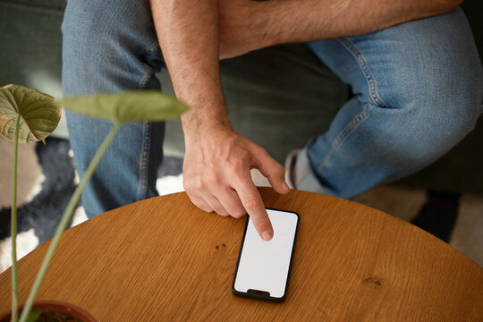 Anonymous man scrolling on blank screen phone.