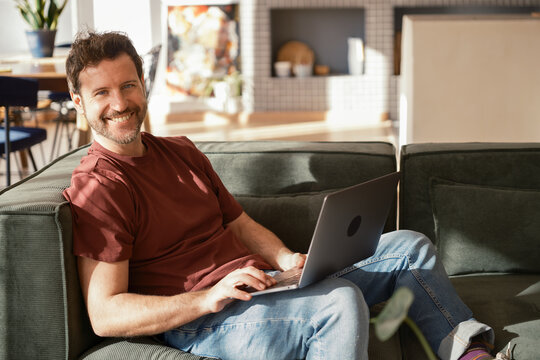 Cheerful man using laptop and looking at camera